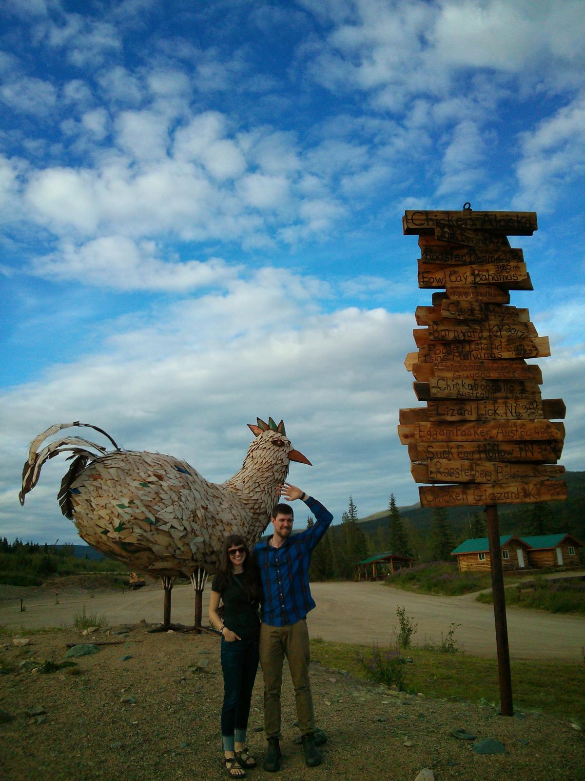 Ryan and his wife posing outside near a giant chicken sculpture
