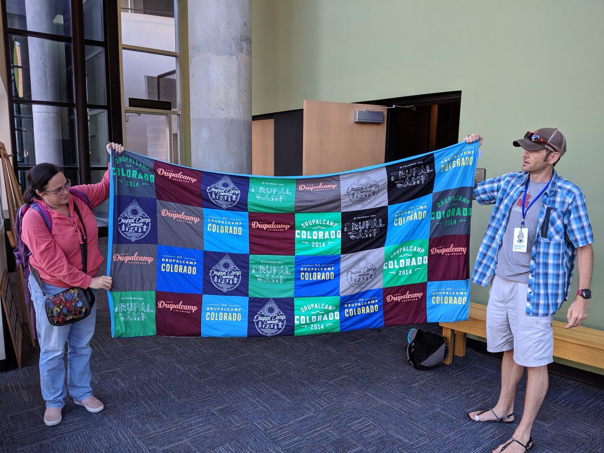 Aimee hannaford holding quilt of old drupal camp colorado t-shirts