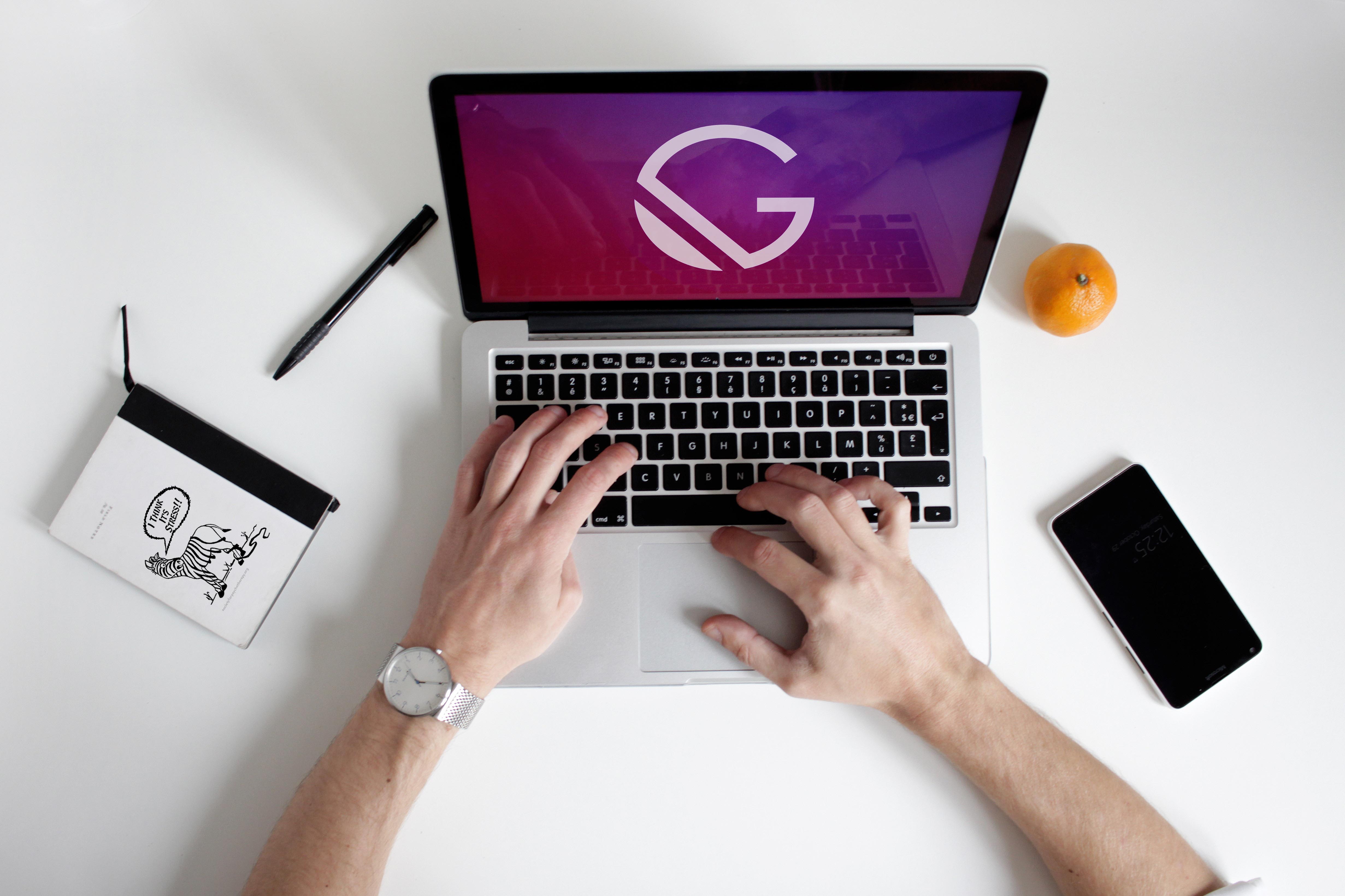 Man sitting at desk typing on laptop with gatsby.js logo on the screen