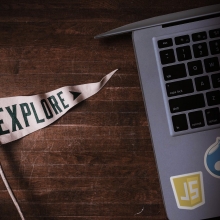 Explore pennant next to laptop with javascript and drupal stickers