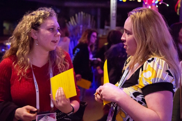 2 women discussing life, the universe, and everything over some bingo cards at the Women In Drupal Party.