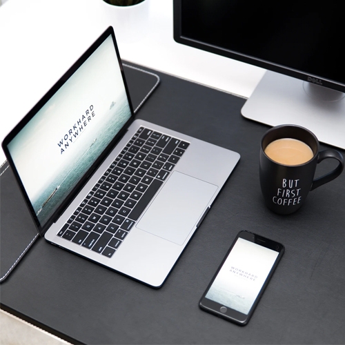 Desk space showing coffee phone and laptop with words work hard anywhere